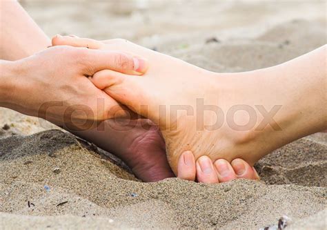 foot massage on a beach in sand male and female caucasian stock