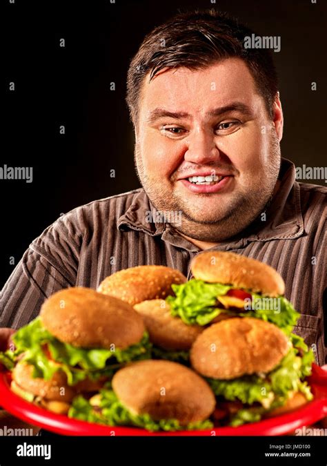 Fat Man Eating Fast Food Hamberger And Carries Treat For Friends On Tray Breakfast For