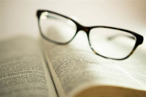 Words Focused On A Book With Reading Glasses On The Background