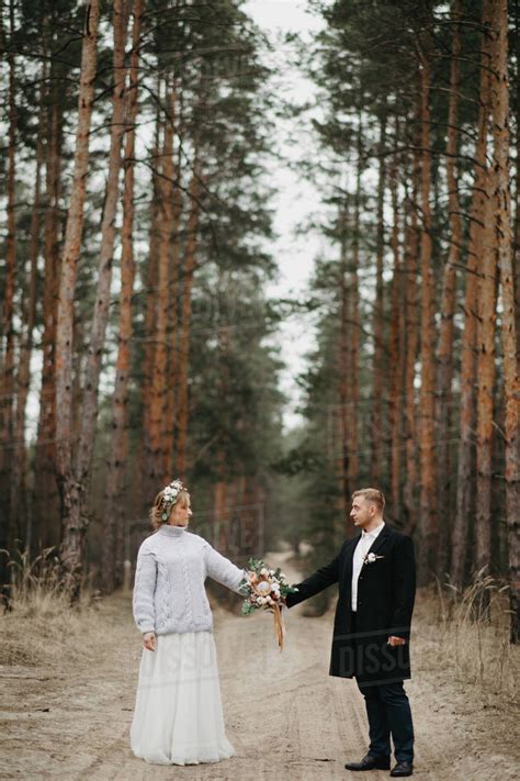 Newlyweds Hold Hands And Walk Along A Forest Path In A Coniferous