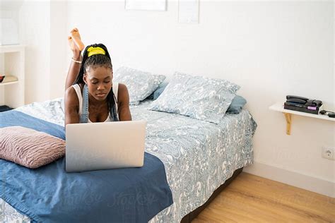 black girl lying on the bed at home with laptop by stocksy contributor luis velasco stocksy