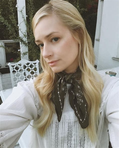 A Woman With Long Blonde Hair Wearing A White Blouse And Black Scarf On