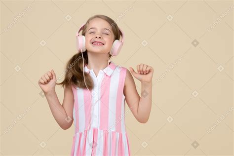 Фото Милая маленькая девочка в наушниках слушает музыку