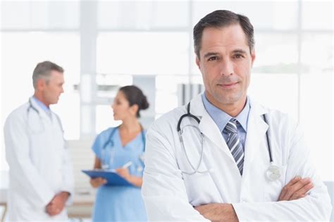 Premium Photo Doctor Looking At Camera While His Colleagues Works