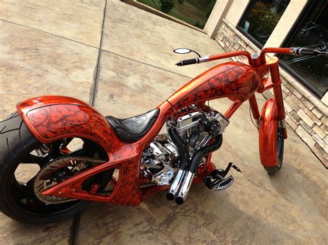 an orange and black motorcycle parked on top of a cement floor next to