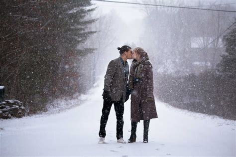Romantic Couple Kissing While Standing On Snowy Field During Snowfall