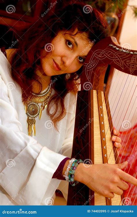 Girl Harpist In White Dress With Jewels Playing Her Instrument Stock