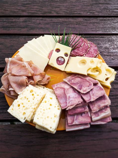 Slices Of Various Cheeses Sausages And Meat Are Arranged On A Plate