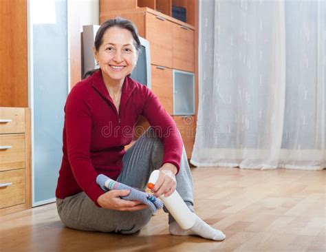 Mature Woman Rubbing Wooden Floor With Rag And Cleanser Stock Image