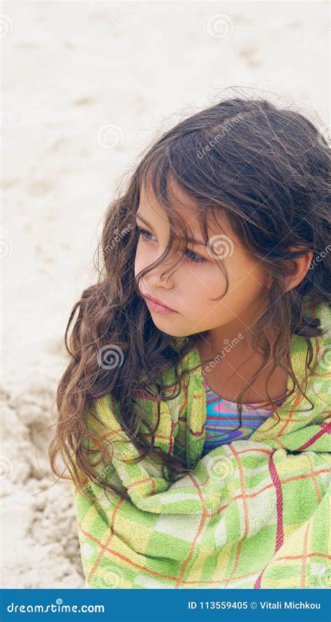 cute little latin girl at beach covered with green towel looking into the distance stock image