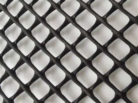 A Piece Of Black Plastic Mesh With Diamond Meshes On The White Background