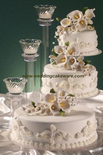 A Wedding Cake With White Flowers On Top And Wine Glasses Next To It