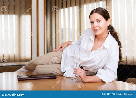 Cheerful Young Female With Glass Of Champagne Posing At Office Stock
