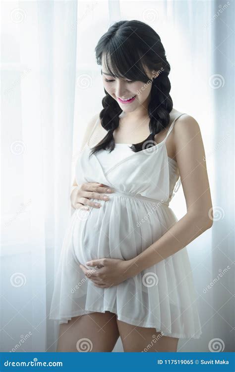 Young Pregnant Asian Woman Holds Her Hands On Her Swollen Belly Love Concept Stock Image