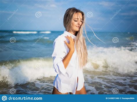 A Tanned Girl In A Blue Swimsuit And A Light Shirt Enjoys The Summer At