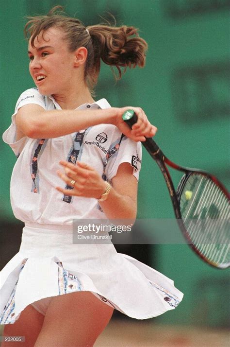 A Woman Swinging A Tennis Racquet At A Ball