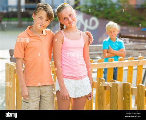 Lächelnde Junge Und Mädchen Gehen Im Abstand Von Ihrem Traurigen Freund Stockfotografie Alamy