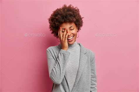 Overjoyed Dark Skinned Female Entrepreneur Laughs Positively Stands With Closed Eyes Laughs At
