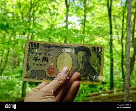 Hand Holding 1000 Yen Japanese Yen Billnote With Nature Background