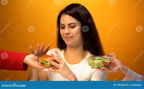 Hungry Girl Choosing Hamburger Instead Of Salad Cheap Junk Food Vs Healthy Diet Stock Image