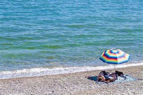couple in swimsuit at the beach sitting under umbrella editorial stock image image of sand