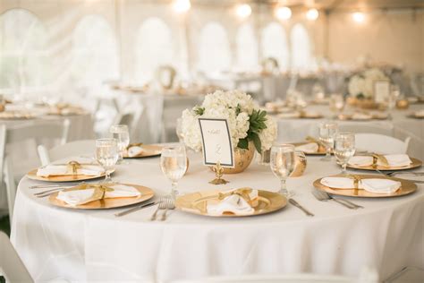 ivory and gold accents provide an elegant table setting at this outdoor wedding reception at s