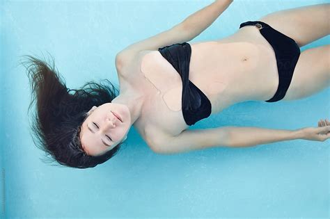 Woman Floating In Water In Swimming Pool By Stocksy Contributor