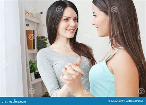Young Lesbian Couple In A Bedroom Looking At Mobile Phone Smiling