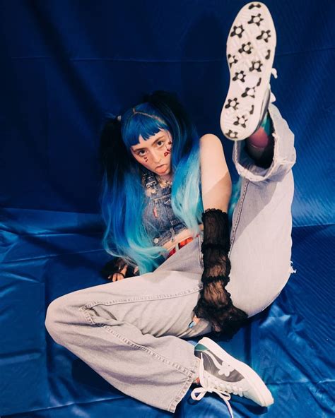 a woman with blue hair and black stockings laying on the ground next to a pair of shoes
