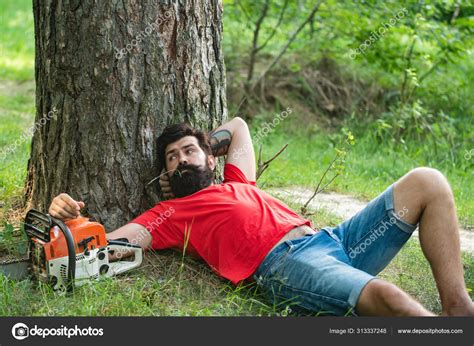 resting after hard work lumberjack worker with chainsaw in the forest man doing mans job