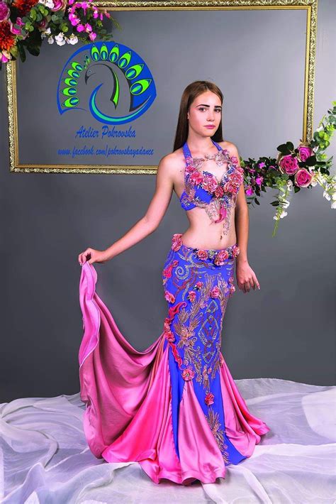A Woman In A Pink And Blue Belly Dance Outfit With Flowers Around Her
