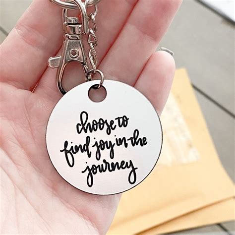 A Hand Holding A Keychain That Says Choose To Find Joy In The Journey