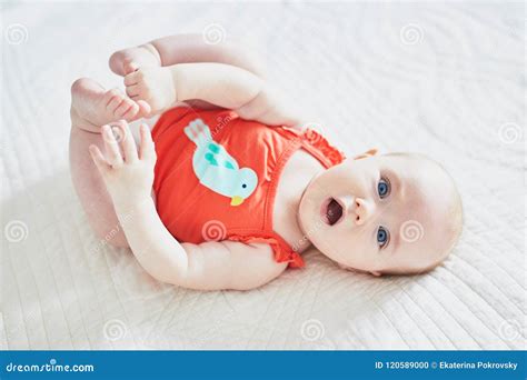Baby Girl Lying On Her Back And Touching Her Feet Stock Photo Image