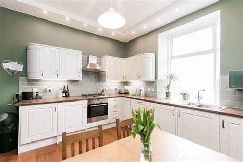 Kitchen features a plank ceiling over sage green cabinets with brass pulls, sage green wooden kitchen hood over white marble slab. This muted sage green is the perfect way of adding subtle ...