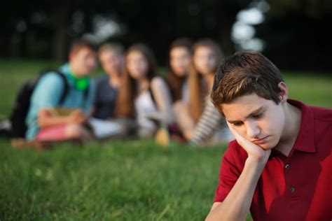 Teenage Boy Feeling Sad Being Watched By A Group Of Friends In The
