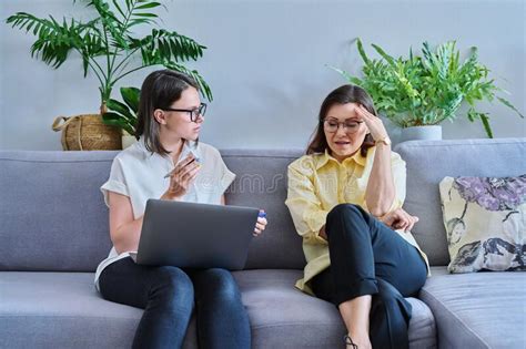 female psychologist and middle aged woman patient sitting together on couch in office stock