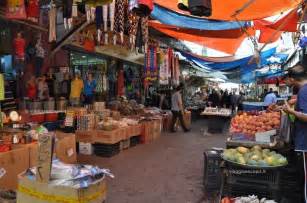 An Outdoor Market With Lots Of Fruit And People Shopping For Goods On