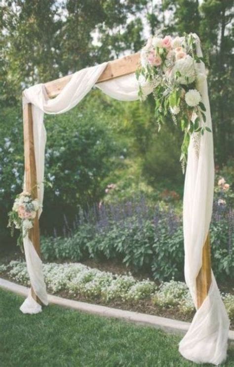 An Outdoor Wedding Ceremony Setup With White And Gold Draping On The Arbors
