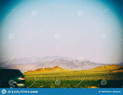 Car Passing By With Mountains On The Desert Landscape Stock Image