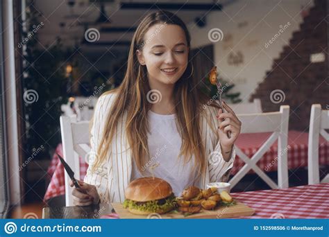 Brunette Girl With Long Hair In A Restaurant Appetizing Eating Potatoes