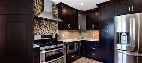 Modern kitchen boasts sleek white cabinetry beautifully contrasted with black appliances and countertops. Jarlin Cabinetry : Ebony Shaker - Royal Kitchen and Flooring