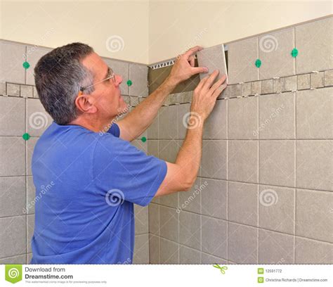 How to tile a bathtub wall sale, in a systematic manner. Man Installing Ceramic Tile In Bathroom Stock Photo ...