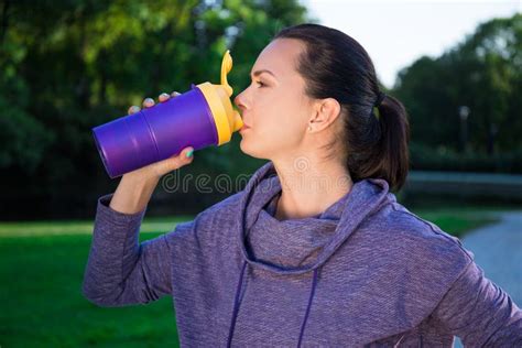 Close Up Of Fitness Woman Drinking Water From Bottle In Park Stock