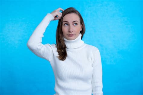 Premium Photo Woman Having Doubts While Scratching Head On Isolated Blue Wall
