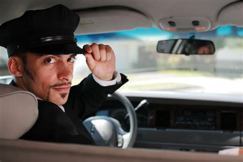 Portrait Of A Handsome Male Chauffeur Sitting In A Car Saluting A