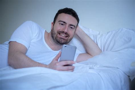 Smiling Man Using His Smart Phone Lying In Bed Stock Image Image Of