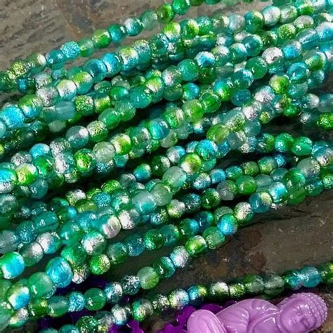 Green And Purple Glass Beads Are Laying On The Ground