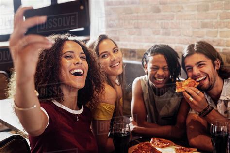 Group Of Happy Multiracial Friends Taking Selfie On A Smart Phone While Having Party At Pizza