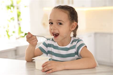 Cute Little Girl Eating Yogurt At Table In Kitchen Stock Image Image