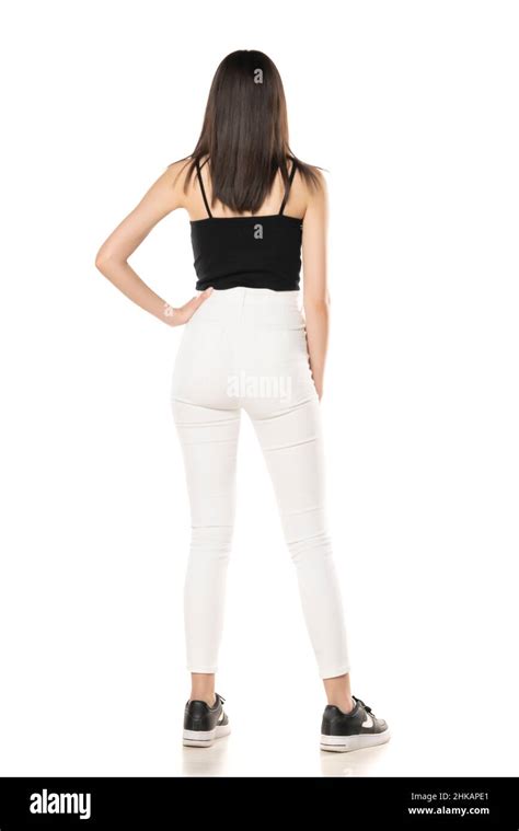 Rear View Of A Teenage Girl In White Jeans And A Black Shirt Stands On